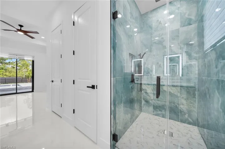 Full bath featuring marble finish floor, a marble finish shower, and ceiling fan
