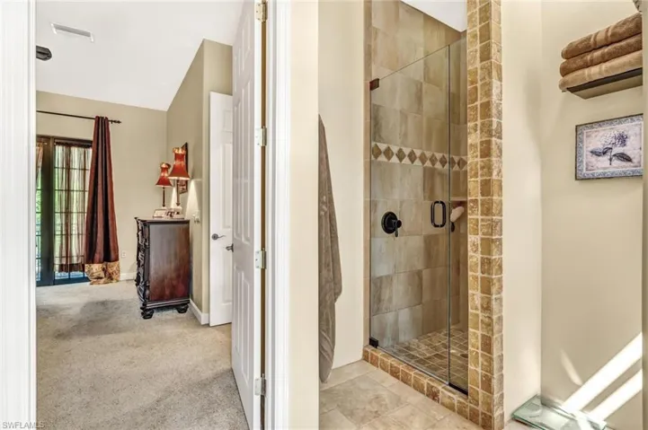 Full bath featuring a shower stall, baseboards, visible vents, and lofted ceiling