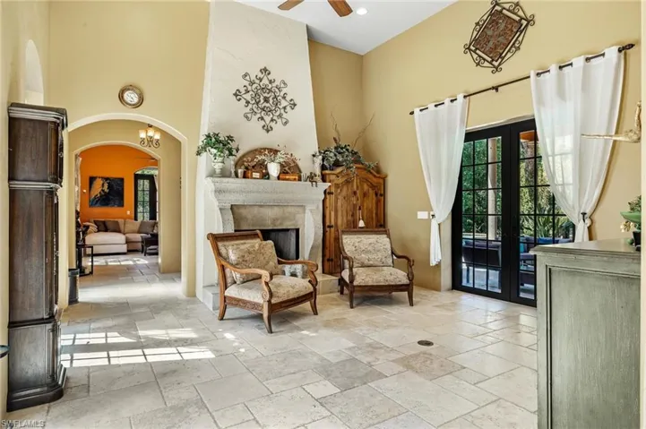 Sitting room featuring arched walkways, ceiling fan, stone tile flooring, and a towering ceiling