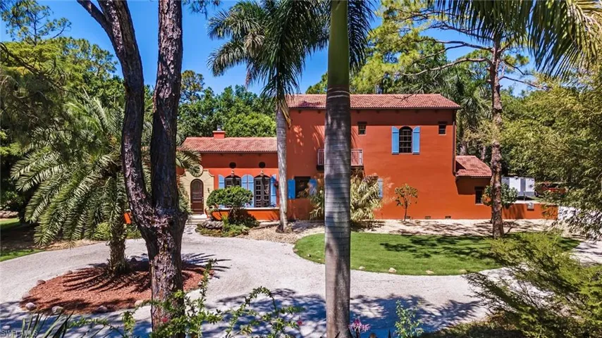 View of front of house featuring curved driveway, a chimney, stucco siding, a front lawn, and a tiled roof