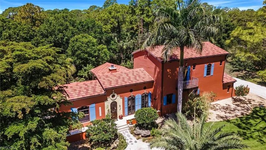 View of front of house featuring stucco siding, a tile roof, a view of trees, and dirt driveway