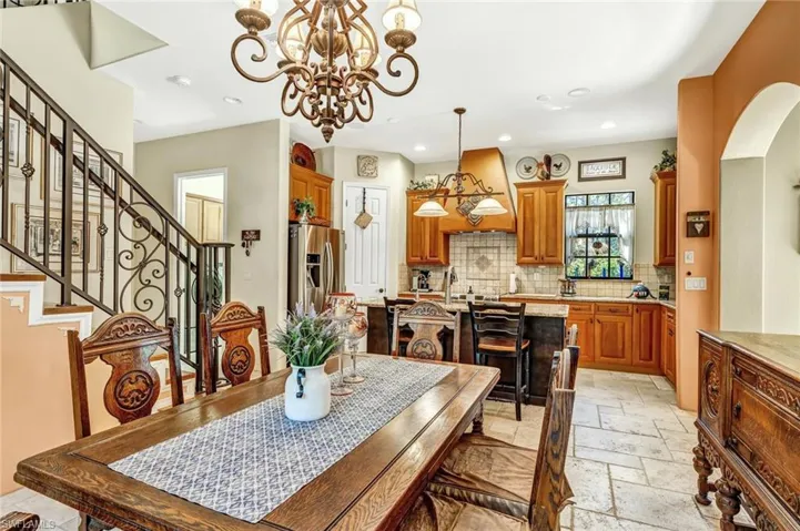 Dining space featuring stairway, recessed lighting, stone tile flooring, arched walkways, and an inviting chandelier