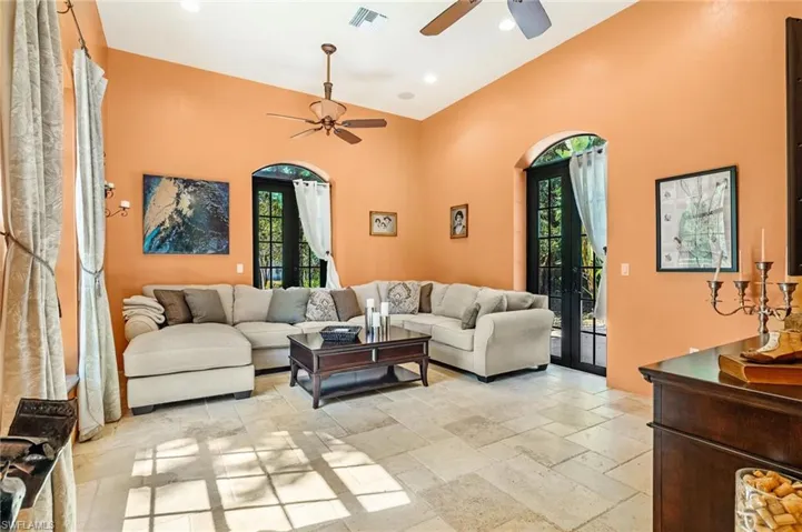 Living room featuring a wealth of natural light, visible vents, stone tile floors, and a ceiling fan
