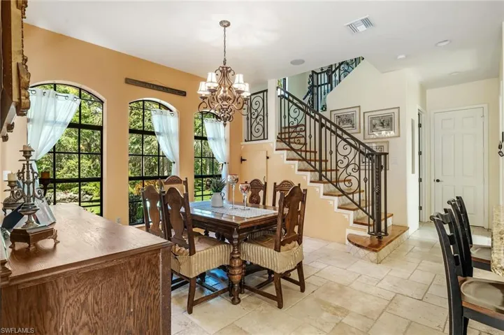 Dining room featuring stairs, visible vents, stone tile flooring, and a chandelier