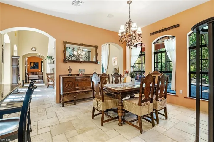 Dining area featuring visible vents, arched walkways, stone tile flooring, and a chandelier
