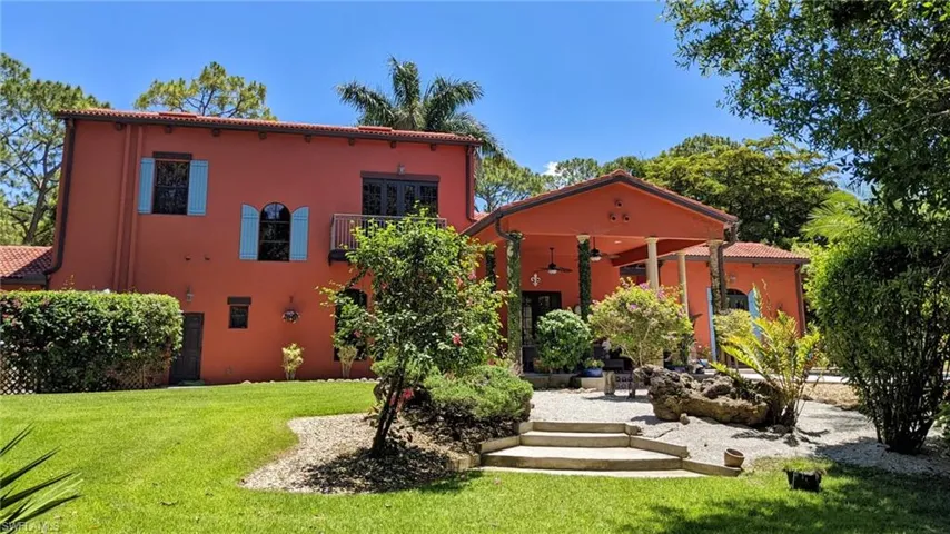 Back of property with a tile roof, stucco siding, and a lawn