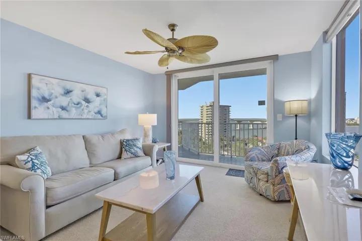 Carpeted living room featuring healthy amount of natural light, expansive windows, and ceiling fan