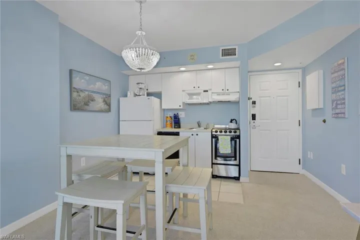 Kitchen featuring white cabinets, white appliances, light carpet, and light countertops