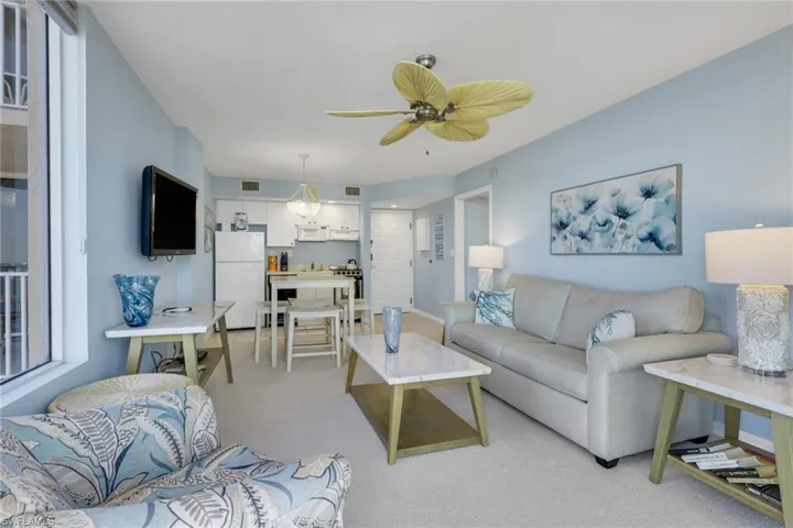 Living area with light colored carpet and a ceiling fan