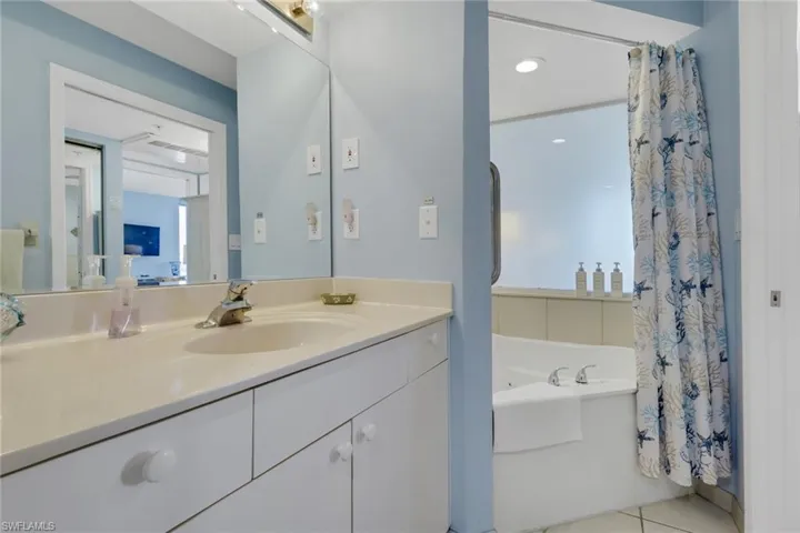 Full bath with a garden tub, vanity, a shower with shower curtain, light tile patterned flooring, and recessed lighting