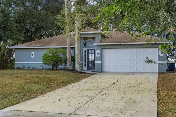 View of front of house featuring stucco siding, driveway, a front lawn, roof with shingles, and an attached garage