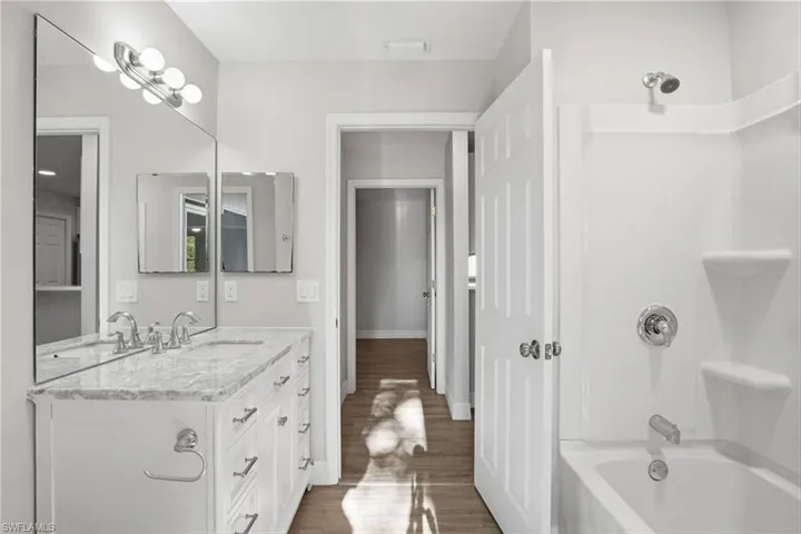Bathroom featuring vanity, bathing tub / shower combination, and dark wood-style floors