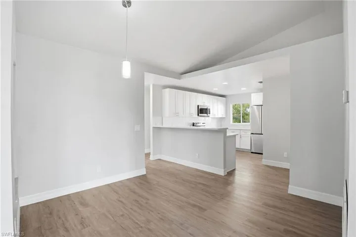 Kitchen with white cabinetry, light countertops, a peninsula, pendant lighting, and stainless steel appliances