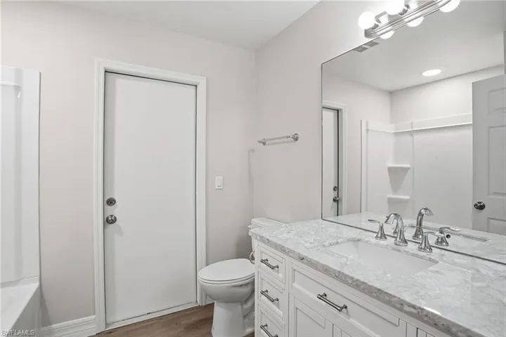Bathroom featuring vanity, dark wood-type flooring, and shower / bathtub combination