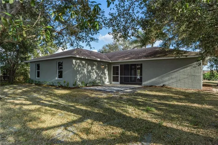 Back of house featuring a patio area, a lawn, and stucco siding
