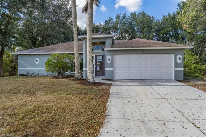 Ranch-style house featuring stucco siding, concrete driveway, a front lawn, and a garage