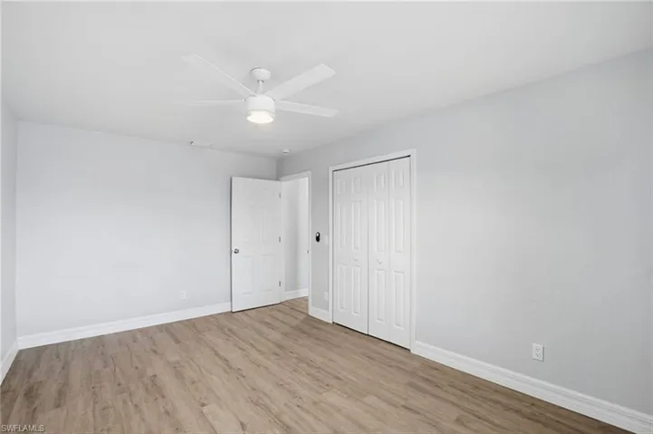 Unfurnished bedroom featuring light wood-style floors, a closet, and a ceiling fan