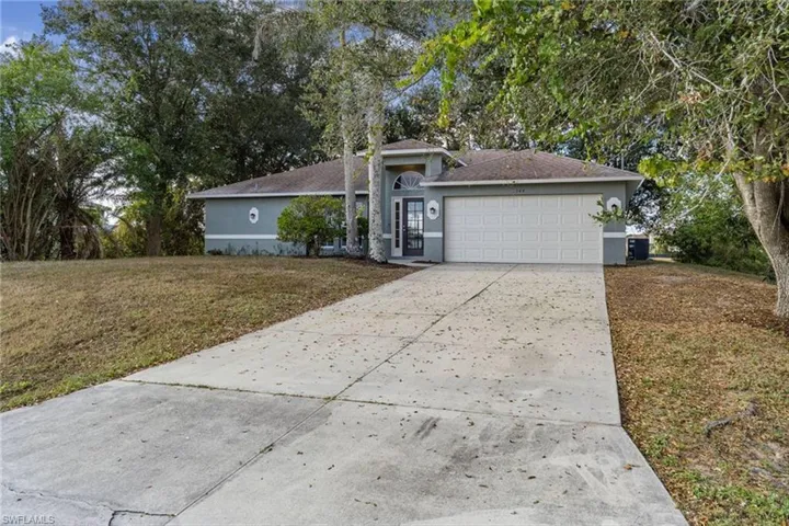 Ranch-style house featuring stucco siding, concrete driveway, a front lawn, an attached garage, and a shingled roof