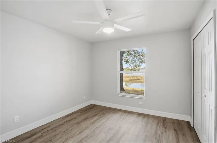 Unfurnished bedroom with a closet, light wood-style flooring, a ceiling fan, and a water view