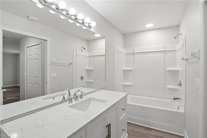 Full bath featuring vanity, dark wood finished floors, and tub / shower combination
