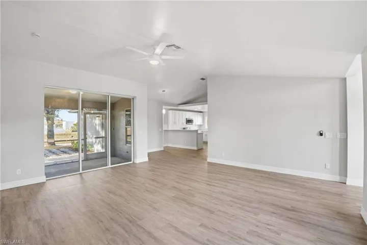 Unfurnished living room featuring a ceiling fan, vaulted ceiling, and light wood finished floors