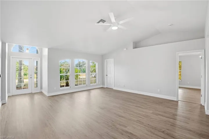 Unfurnished living room featuring wood finished floors, lofted ceiling, and a ceiling fan
