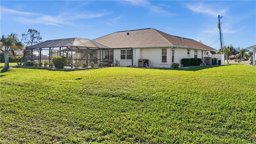 Rear view of house featuring glass enclosure and a lawn