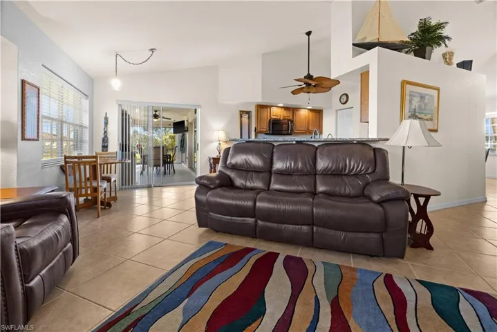 Tiled living room featuring ceiling fan and high vaulted ceiling