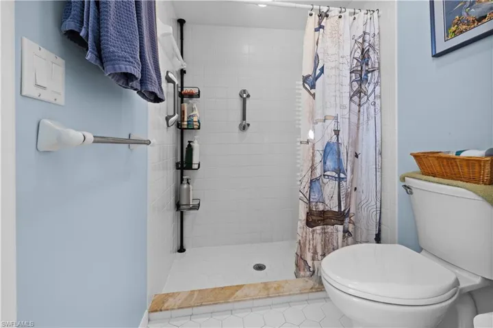 Bathroom featuring tile patterned floors, toilet, and walk in shower