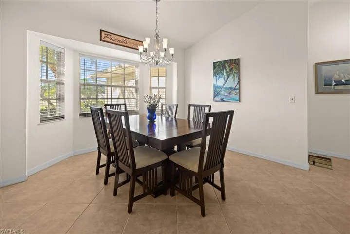 Dining room featuring light tile patterned flooring, vaulted ceiling, and an inviting chandelier