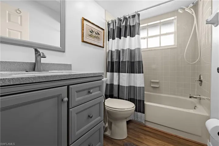 Full bathroom featuring vanity, toilet, shower / bathtub combination with curtain, and hardwood / wood-style flooring