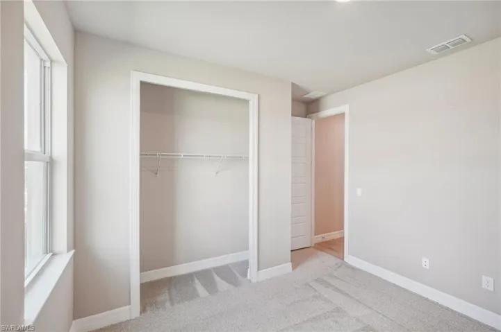 Unfurnished bedroom featuring a closet and light colored carpet