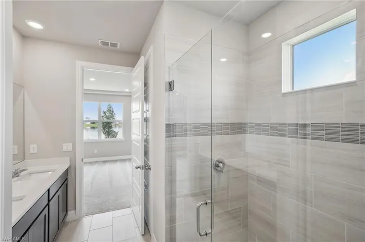 Bathroom featuring walk in shower, a water view, vanity, and tile patterned floors