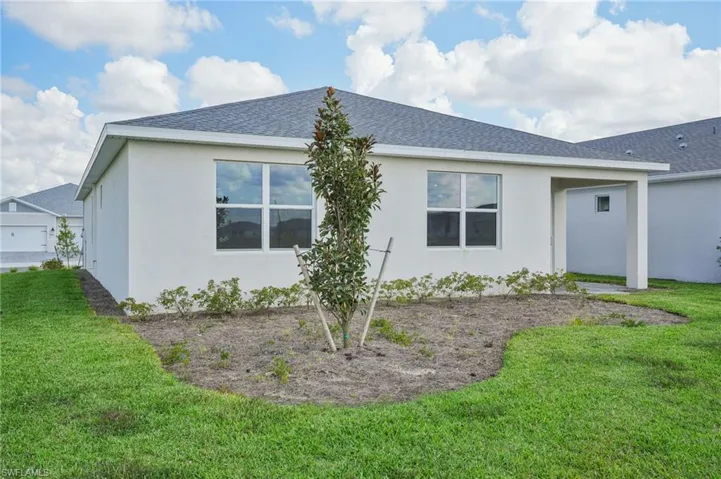 Rear view of property featuring a garage and a yard