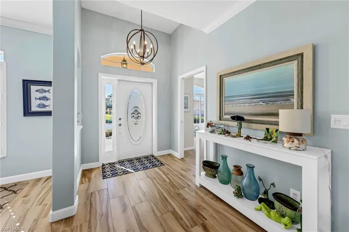 Foyer with crown molding, a chandelier, and light hardwood / wood-style flooring