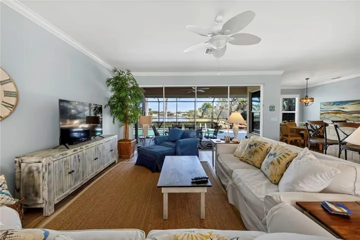 Living room with crown molding, ceiling fan, and light hardwood / wood-style floors