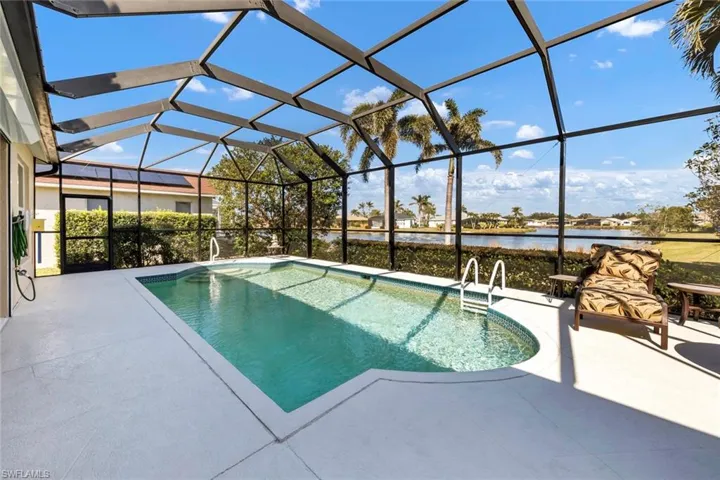 View of pool featuring a patio, a water view, and glass enclosure