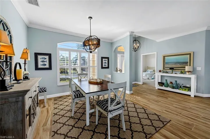 Dining space with ornamental molding, light wood-type flooring, and a chandelier