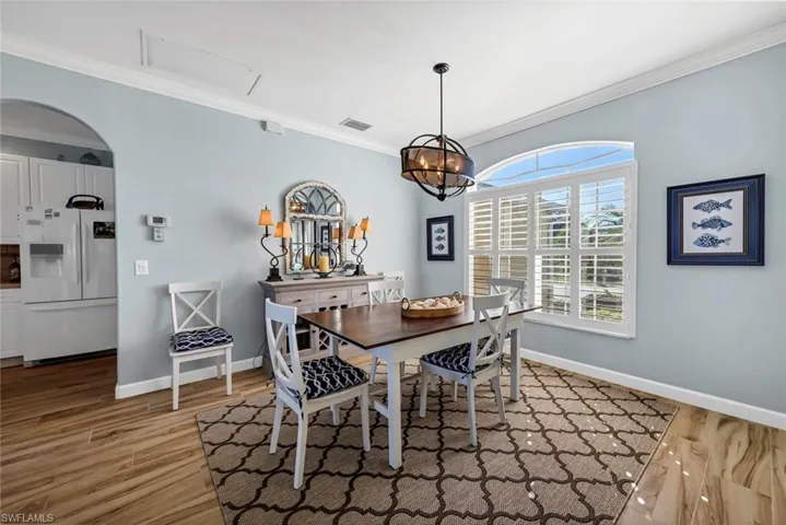 Dining area with crown molding, a notable chandelier, and light wood-type flooring