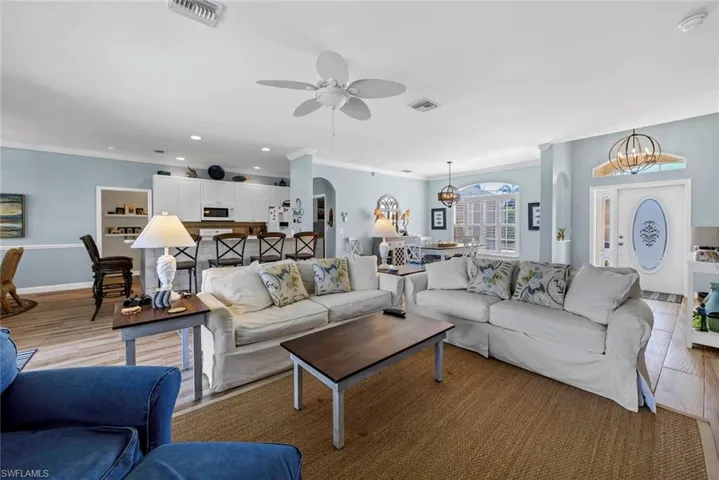 Living room with crown molding, ceiling fan with notable chandelier, and light hardwood / wood-style floors