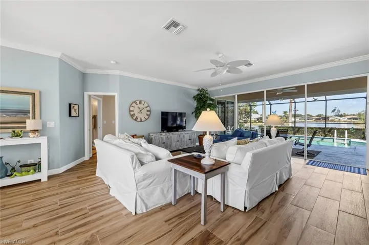 Living room featuring crown molding, light hardwood / wood-style floors, and ceiling fan