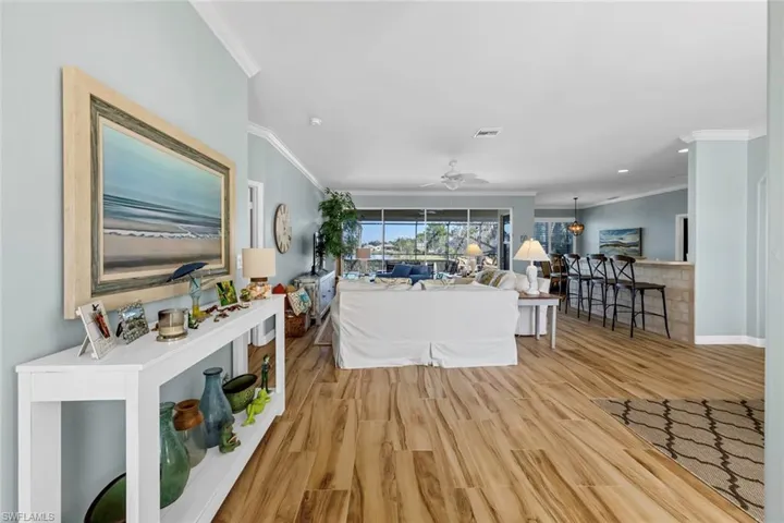 Living room featuring light hardwood / wood-style flooring, ornamental molding, and ceiling fan