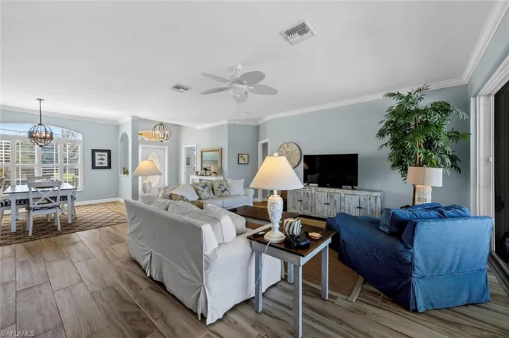 Living room featuring hardwood / wood-style flooring, ornamental molding, and ceiling fan with notable chandelier