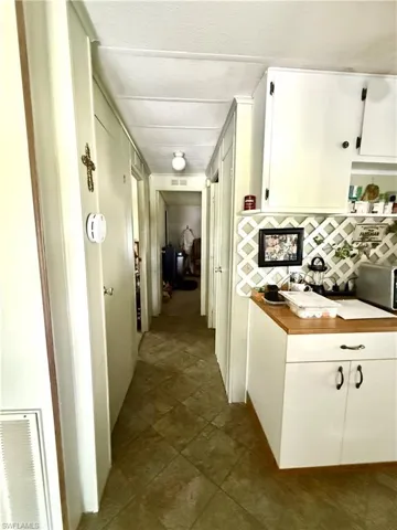 Hallway with tile flooring, white paneling, and a flush-mount ceiling light