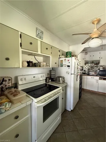 Kitchen featuring white appliances, upper and lower cabinetry, and a ceiling fan