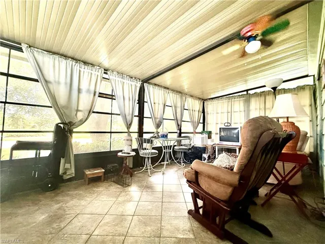 Enclosed sunroom featuring full-height windows, a paneled ceiling, and tile flooring