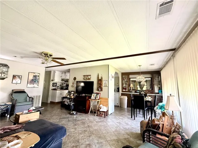 Open-concept living space with tile flooring throughout, featuring a ceiling fan in the living area and a built-in dining hutch with mirrored backing
