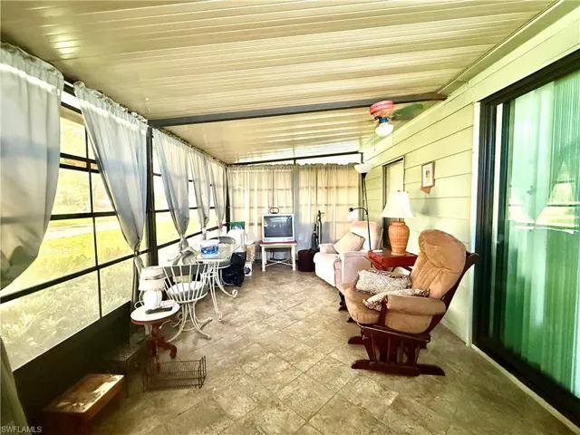 Enclosed patio featuring a flat panel ceiling, large windows with vertical blinds, tile flooring, and a ceiling fan