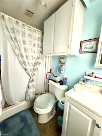 Compact bathroom featuring a shower/tub combination, white vanity with integrated sink, white upper cabinetry, and a ceiling-mounted ventilation grate