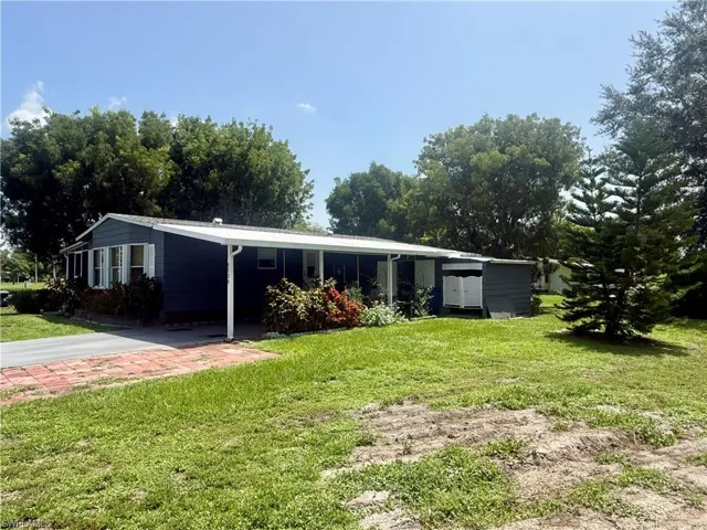 Single-story residence featuring dark siding, white window shutters, and a covered carport